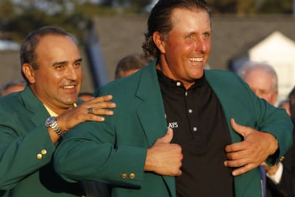 Mickelson se pone la chaqueta verde ayudado por Ángel Cabrera, el ganador de la anterior edición.