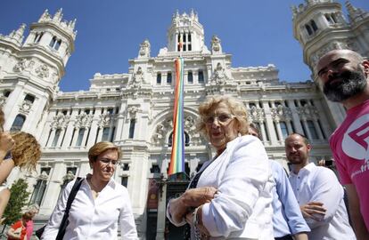 La alcaldesa de Madrid, Manuela Carmena, asiste al despliegue de la bandera arco iris en la fachada del Palacio de Cibeles.