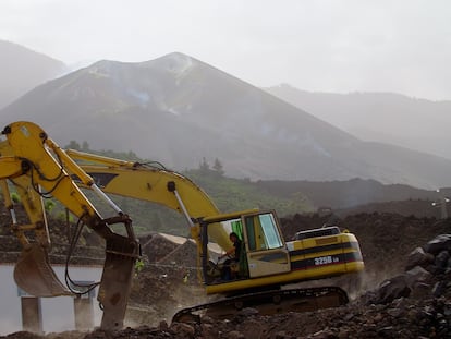 Una excavadora retira la lava en El Paraíso (El Paso) con el volcán de Cumbre Vieja al fondo.