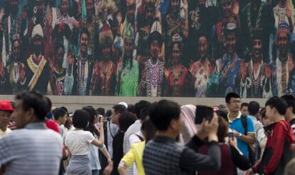 Una multitud en la plaza de Tiananmen, en mayo, frente a una pantalla que muestra a uigiures vestidos con trajes regionales