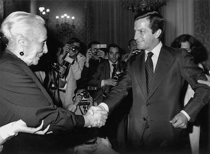 Adolfo Suárez y la dirigente histórica del PCE, Dolores Ibárruri, 'La Pasionaria', se estrechan la mano en la primera sesión de las Cortes Democráticas del 14 de julio de 1977. De la expectación existente ante este encuentro da fe la cantidad de fotógrafos que se ve al fondo de la imagen.