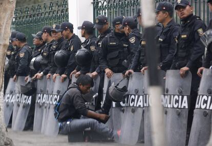 Un limpiabotas repasa las botas de un policía mientras hacen guardia en el exterior del Congreso de Lima (Perú).