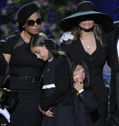 A filha de Michael Jackson, Paris, apoiada em Janet Jackson durante as cerimônias fúnebres de seu pai. Ela alertou para o fato de que seu pai não canta no disco póstumo.