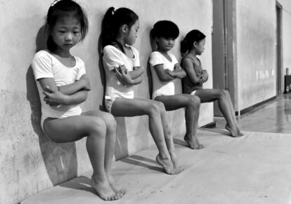 Imagem ganhadora do segundo prêmio da categoria 'Vida Cotidiana', do fotógrafo Tiejun Wang. Na imagem, chamada 'O suor fabrica campeões', aparecem quatro estudantes da escola de ginástica que realizam flexões de pé durante um treinamento em Xuzhou (Chinesa).