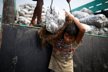 Asma Akter, una refugiada rohingya de 10 años, saca bolsas de pescado congelado de un camión de reparto en el patio de secado de pescado Nazirartek en Cox's Bazar (Bangladesh)