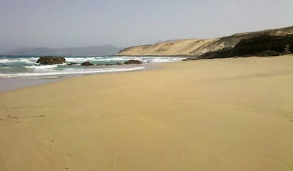 En la impoluta Playa de Agualique (Fuenteventura) el ba&ntilde;o es peligroso, con lo que se trata de pasear y recrearse en este acantilado que se dir&iacute;a nevado por un mar de jable (arena de origen e&oacute;lico), arrastrado por el mismo viento que luego empujar&aacute; las velas de los windsurfistas.