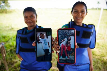 Dos buscadoras de minas muestran fotografías de sus familias en Colombia.