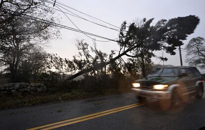 Un coche circula por una carretera donde varios árboles han caido sobre los cables de electricidad tras el paso del huracán Sandy por Darmouth en Massachusetts (Estados Unidos)