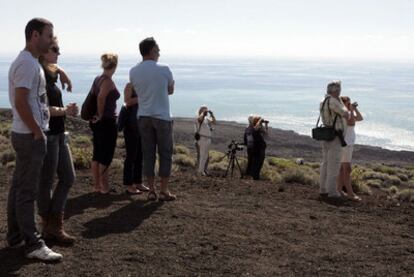 Varios turistas y curiosos observan desde una loma de Puerto Naos, cerca de La Restinga (El Hierro), el volcán submarino.