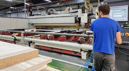 Un trabajador manipula la máquina del centro de chapado de formas curvas.