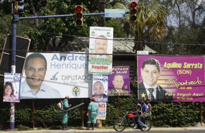 Varios dominicanos pasan ante una multitud de carteles electorales ayer en Santo Domingo.