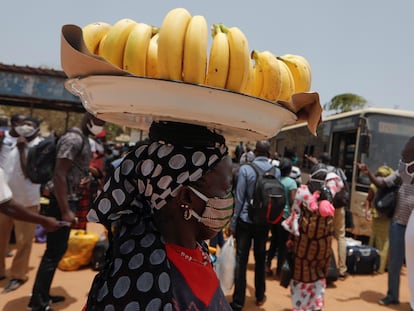 Una vendedora callejera carga con una cesta de plátanos sobre su cabeza por una concurrida calle de Dakar, capital senegalesa, en mayo de 2020.