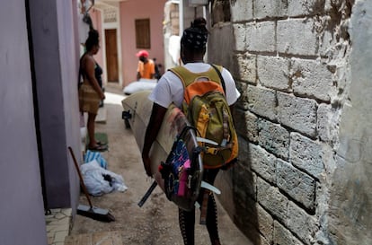 Khadjou Sambe lleva su tabla mientras camina por el barrio de Ngor, Dakar, Senegal el 12 de agosto de 2020. Los residentes de Ngor se han acostumbrado a ver a Sambe cargando su tabla por los callejones que conducen a la orilla.