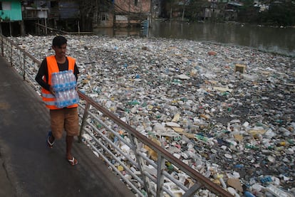 Un hombre carga botellas de agua de plástico junto al río Negro, en el estado brasileño de Amazonas, saturado de basura, sobre todo plásticos. 