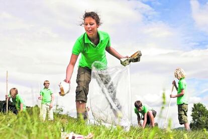 Niños recogiendo basura en un parque.