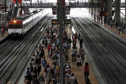 Viajeros esperando el tren en los andenes en la estación de Atocha