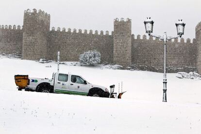 Un vehículo con pala quitanieves esparce sal para derretir la nieve caída en las inmediaciones de la muralla de Ávila, que ha despertado cubierta por un manto blanco como consecuencia del temporal que mantiene en alerta a veintiséis provincias españolas por precipitaciones y rachas de viento.