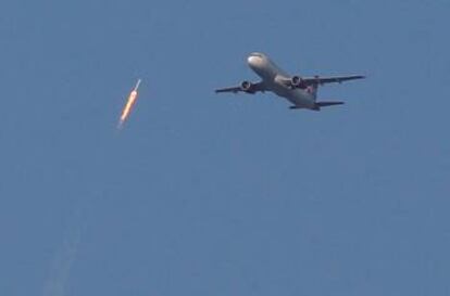El cohete en ascenso sobre un avión.