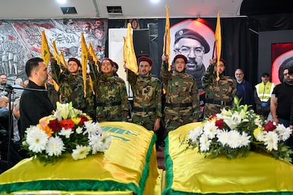 Hezbollah militants stand before the coffins of two fighters killed in an Israeli attack in Beirut.