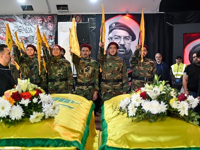 Hezbollah militants stand before the coffins of two fighters killed in an Israeli attack in Beirut.