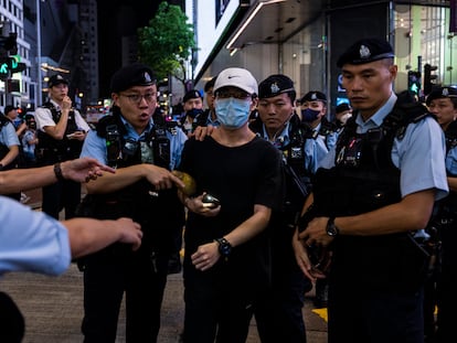 A member of the public is escorted by police after light a smartphone light near Victoria Park, the city's former venue for the annual 1989 Tiananmen massacre vigil, on the 34th anniversary of China's Tiananmen Square crackdown in Hong Kong, Sunday, June 4 2023.
