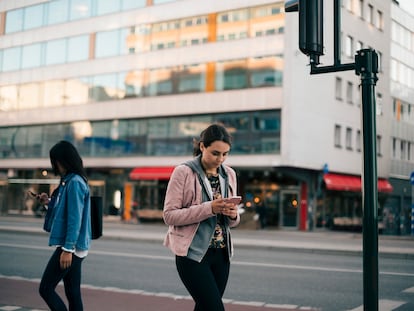 Una mujer camina mirando el móvil.