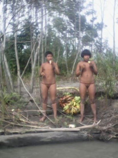 Dos jóvenes indígenas mashco miro, comiendo plátanos cerca del río Madre de Dios. A veces reciben esa fruta de las comunidades ya asentadas.