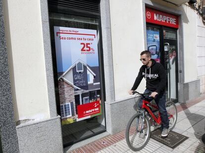 Un ciclista pasa delante de una sucrusal de Mapfre