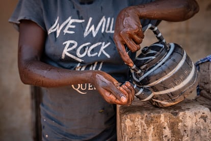 Aminata se refresca con agua en un día en el que las temperaturas de su pueblo en Gambia han alcanzado los 39 grados, con una sensación térmica de 42.