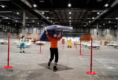 Un trabajador prepara camas en uno de los pabellones del recinto ferial Ifema, que se prepara para albergar 1.300 camas convencionales y 96 de UCI por la crisis del coronavirus.