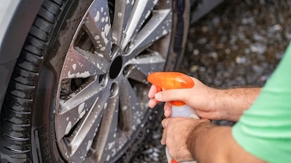 Limpiando llantas de un coche con un limpiador en spray.