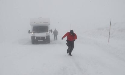 Una persona espera junto a su autocaravana en la N-137, en el puerto de Belagua (Navarra), el paso de una máquina quitanieves que le despeje la carretera y así poder seguir su camino, este domingo.