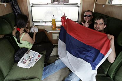 Dos montenegrinos despliegan la bandera serbia en el tren en el que ayer viajaban hacia su país.