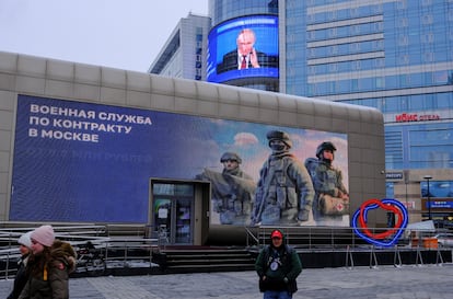 A screen shows Putin's intervention next to the advertising billboard promoting Russian contract military service, on a Moscow street, on December 19. 