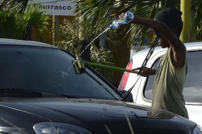 Un ni&ntilde;o limpia el cristal de un coche.