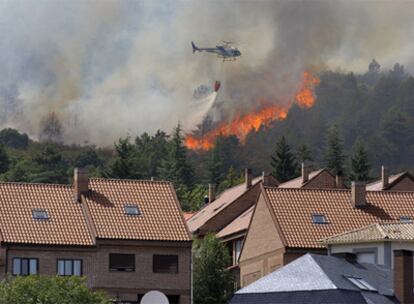 Un helicóptero, en las labores de extinción del incendio en la urbanización Conjunto La Salinera, en Collado Mediano (Madrid).