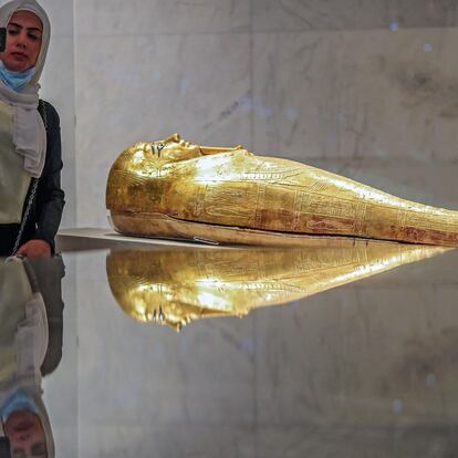 A woman takes a selfie next to a golden sarcophagus at the Museum of Egyptian Civilisation (NMEC), in the Fustat district of Old Cairo, during its official reopening , on April 4, 2021, a day after the Pharaohs' Golden Parade ceremony. - The NMEC which opened its doors to limited exhibits from 2017, opens fully a day after the "Pharaohs' Golden Parade", but the mummies go on display to the general public two weeks later. (Photo by Mahmoud KHALED / AFP)