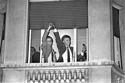 Alfonso Guerra (izquierda) levanta la mano de Felipe González, desde una ventana del hotel Palace de Madrid. Los futuros vicepresidente y presidente del Gobierno, celebran la mayoría absoluta del Partido Socialista Obrero Español (PSOE) en las elecciones legislativas del 28 de octubre de 1982.