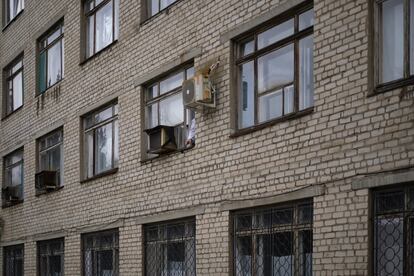 Un sanitario fuma en una ventana que da a la parte trasera del complejo. A escasos metros, se encuentra el edificio destrozado que servía para tratar enfermedades infecciosas. 