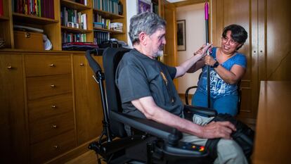 Una empleada del hogar atiende a un hombre en silla de ruedas en Madrid.