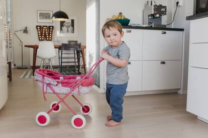 Un niño juega con el carrito de una muñeca. 