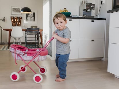 Un niño juega con el carrito de una muñeca. 