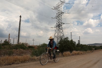 Un hombre monta una bicicleta en una carretera cerca de las líneas de transmisión de alto voltaje cerca de la planta de energía de Tula, propiedad de la compañía eléctrica estatal CFE