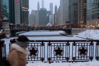 Uma mulher atravessa uma ponte sobre o rio Chicago.