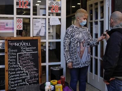 Una empleada de un bar de Sant Just Desvern, en Barcelona, comprueba el certificado covid de un cliente en la entrada del local.