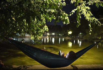 Una mujer consulta su móvil cerca de un lago en Bucarest (Rumanía), el pasado 13 de agosto, durante una ola de calor.