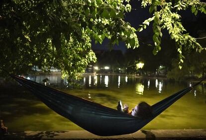 Una mujer consulta su móvil cerca de un lago en Bucarest (Rumanía), el pasado 13 de agosto, durante una ola de calor. 