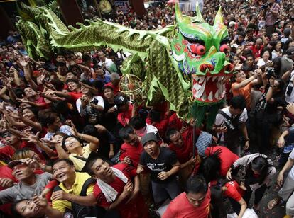 Desfile del dragón por la celebración del Año Nuevo Chino en Biondo, Manila. Los asistentes intentan conger los artículos que se regalan.
