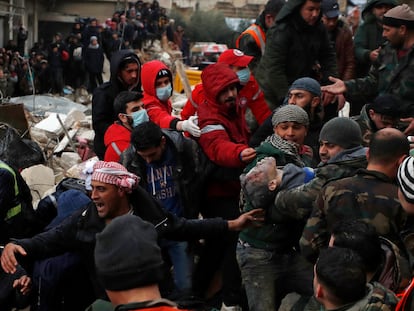 Civil defense workers and security forces carry an earthquake victim as they search through the wreckage of collapsed buildings in Hama, Syria, Monday, Feb. 6, 2023.