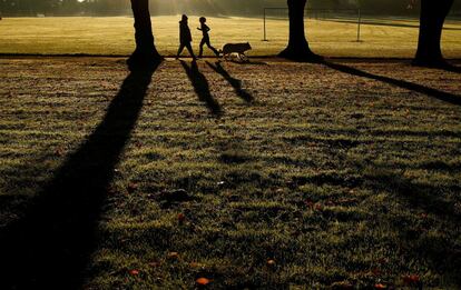 Una mujer que hace deporte se cruza con un perro y su dueño, en el parque Victoria, en Leicester (Reino Unido).